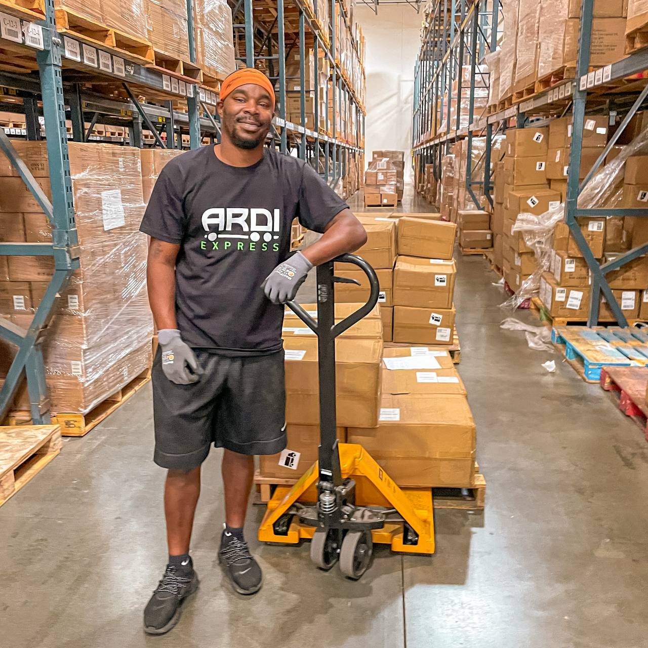ARDI Express floor operator with a pallet jack in a racked aisle of the Edison, New Jersey warehouse