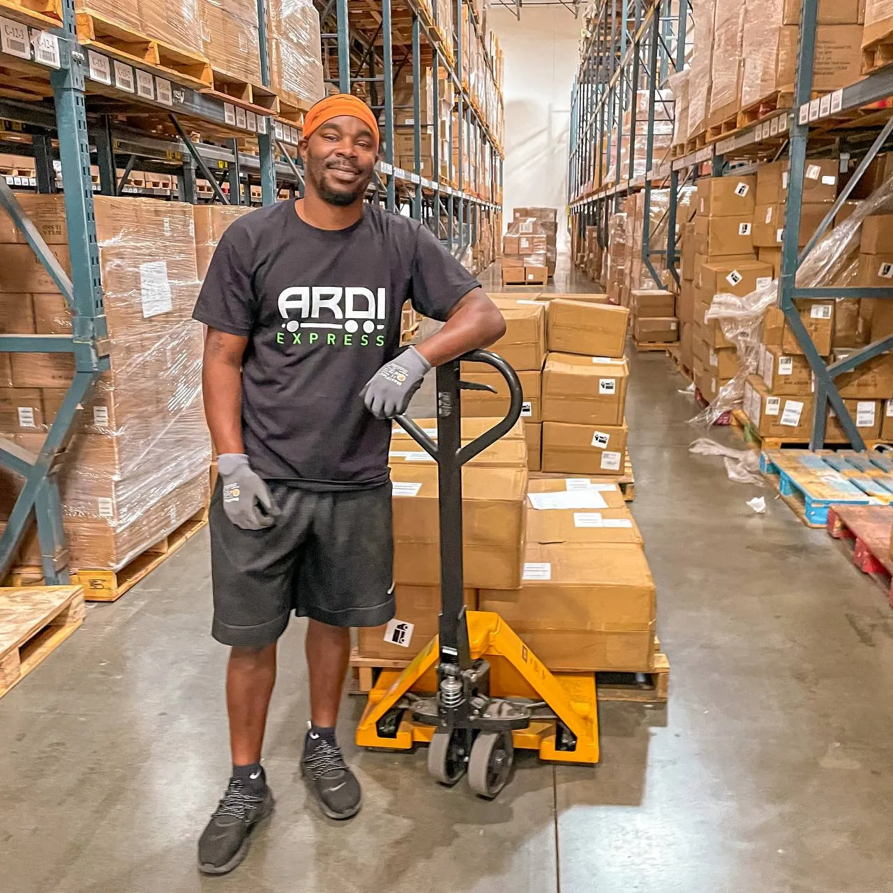 ARDI Express floor operator with a pallet jack in a racked aisle of the Edison, New Jersey warehouse